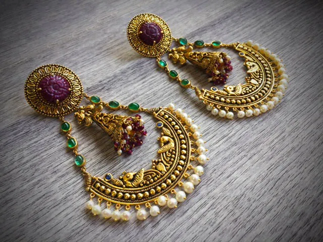 Antique-finish chandbali earrings: carved red stone tops over crescents worked with bird motifs and fringed in pearls