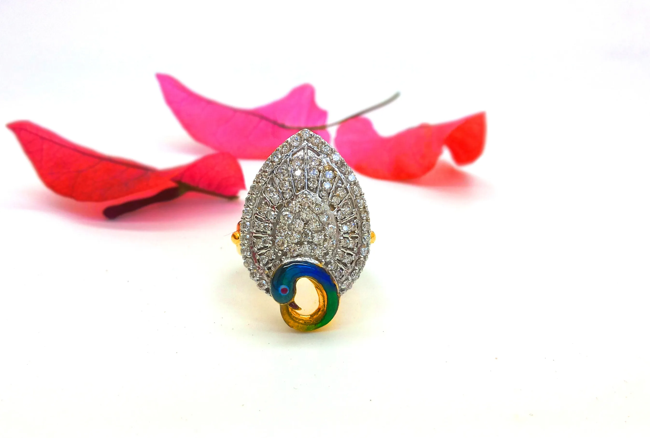 Pear-shaped pavé diamond ring with a small enamel peacock head, among pink petals