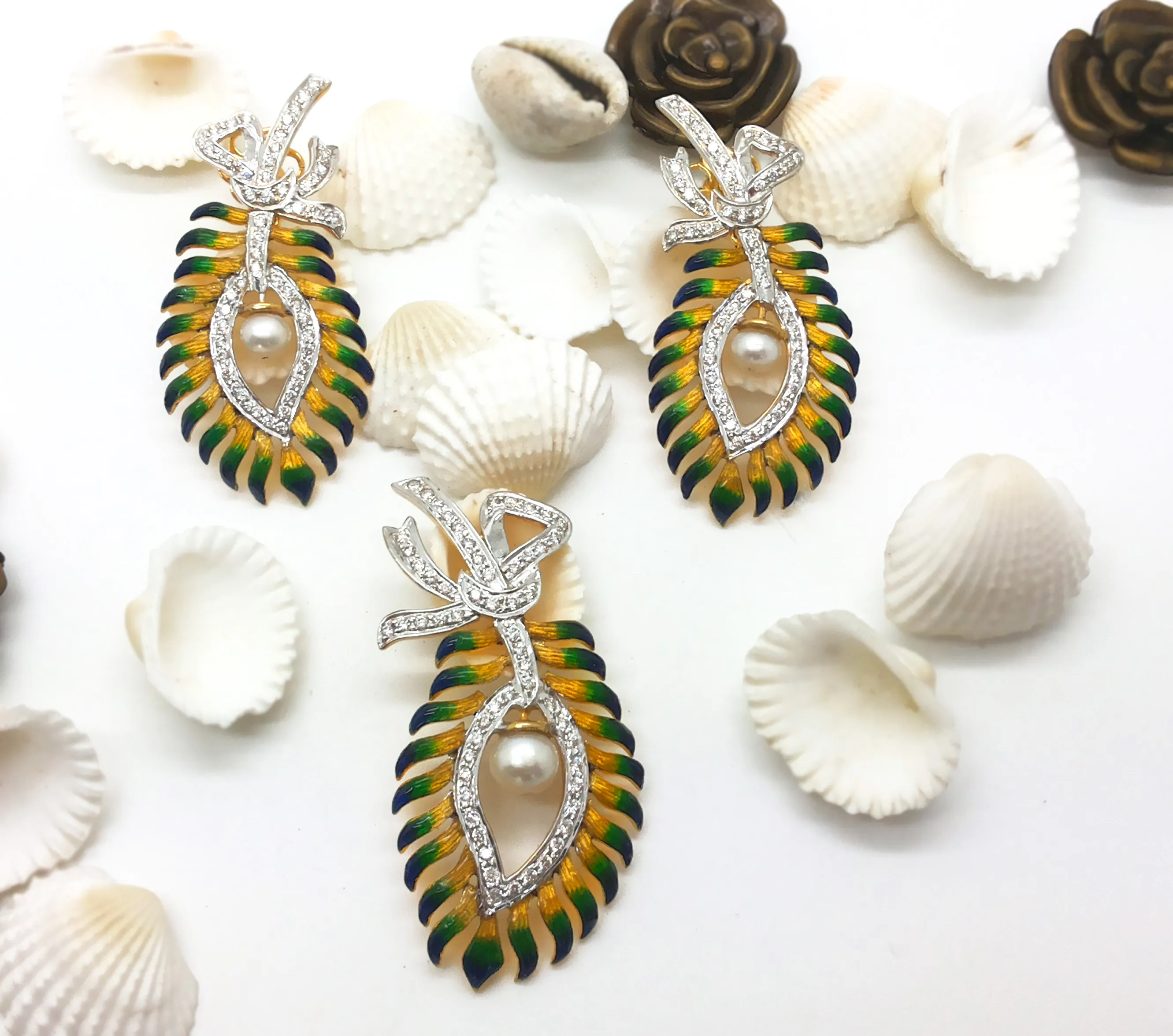 Pendant and earrings shaped as yellow-green enamel feathers with diamond swirls and pearls