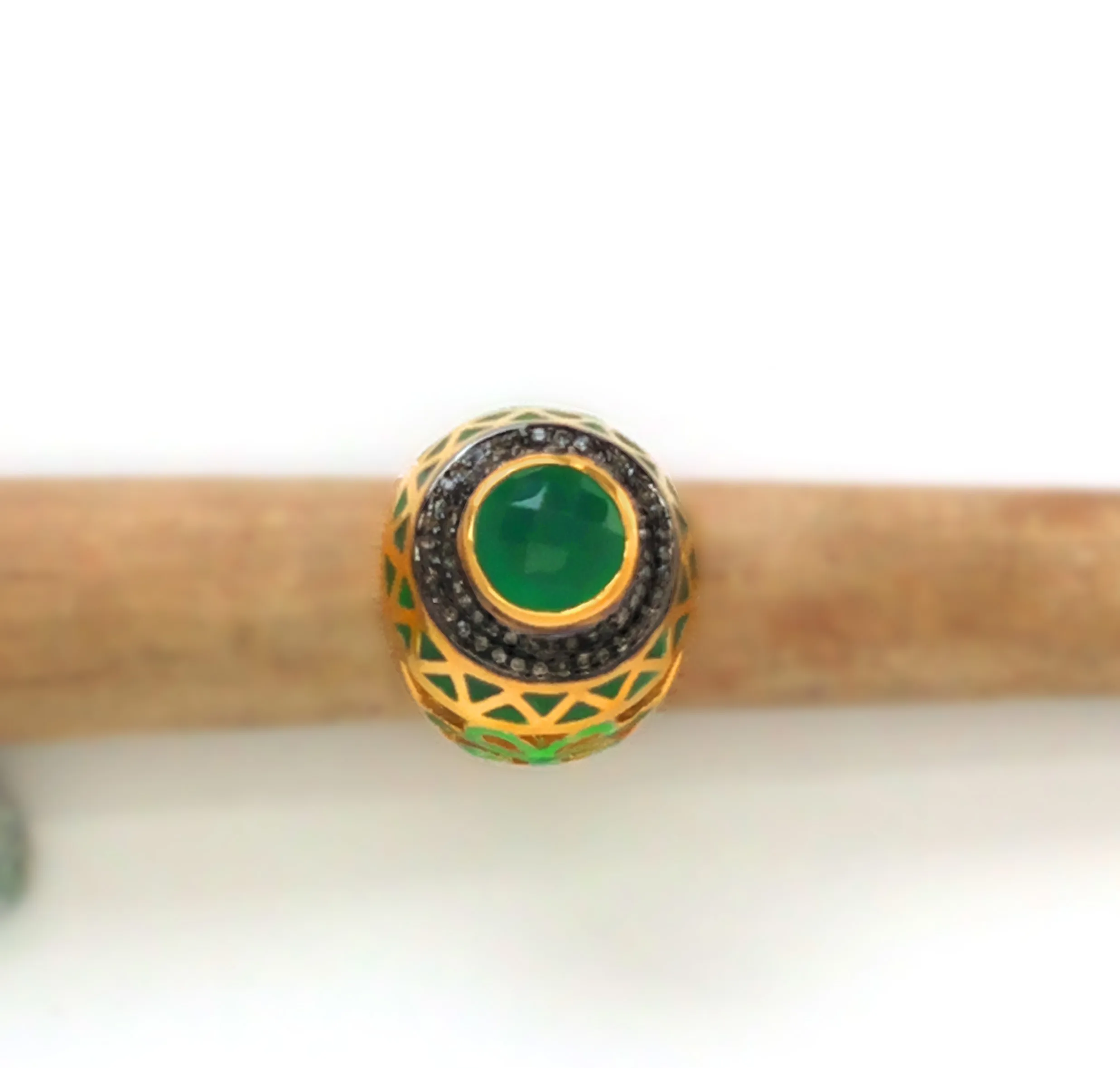 Green cabochon ring resting on a wooden branch, photographed from above