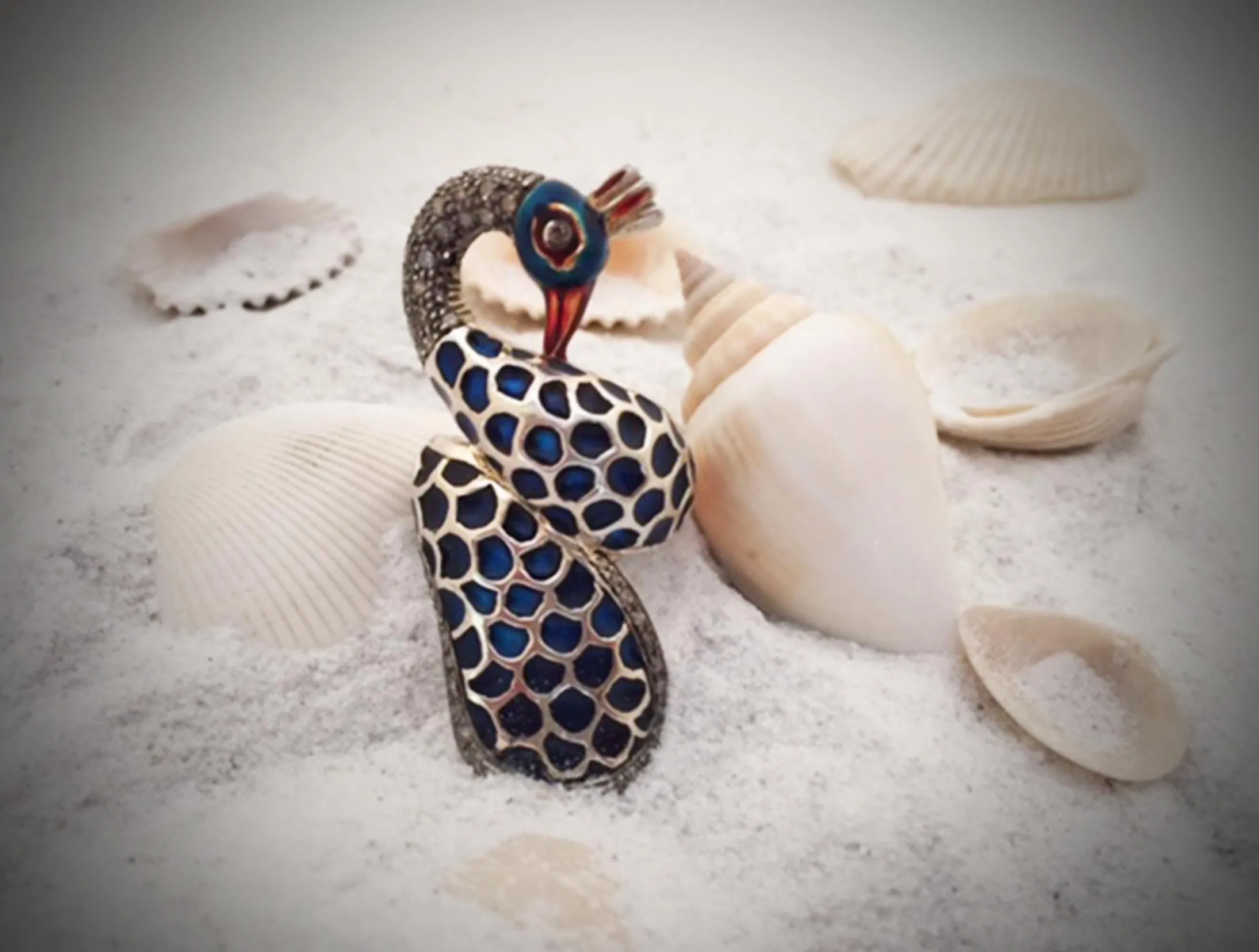 Spotted enamel bird ring styled on white sand among seashells